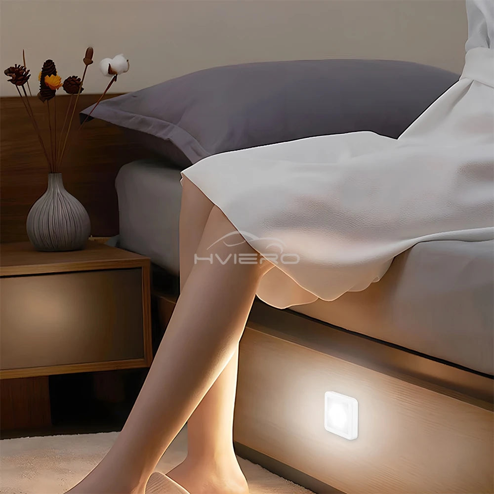 Bedroom scene with a night light on a wooden shelf, next to a bed and a vase with decorative items.