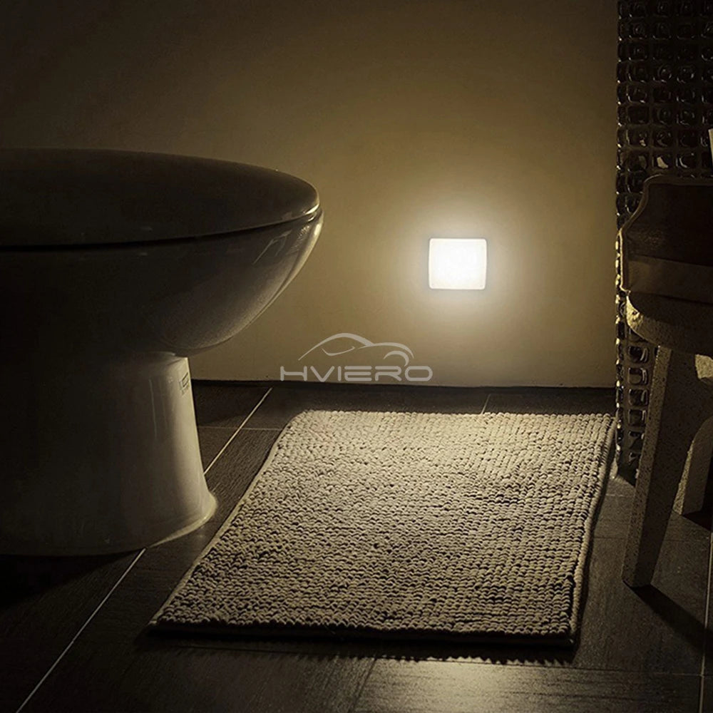 Bathroom with a rug, toilet, and light fixture on the wall.