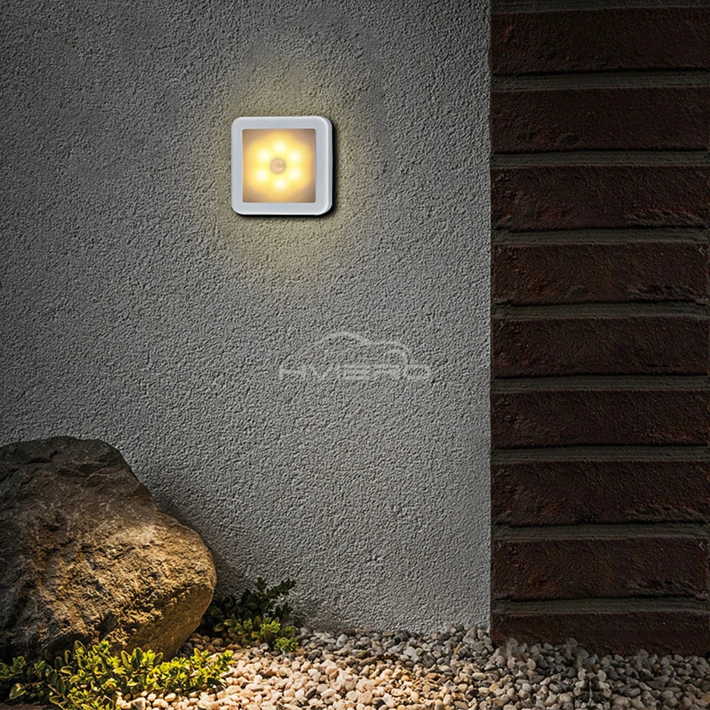 Square outdoor wall light fixture on a textured wall with a natural setting.