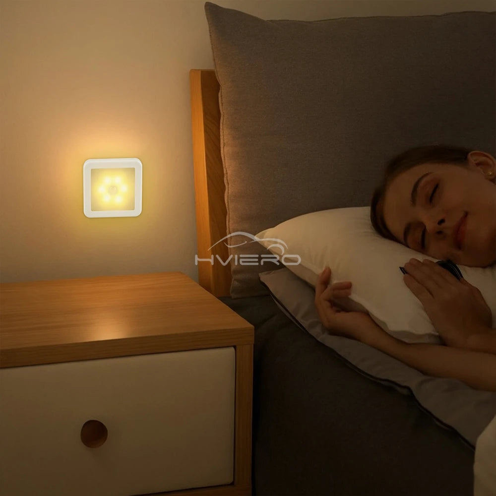 Person sleeping in bed with a night light on a nightstand, brand 'Hvihero' visible.